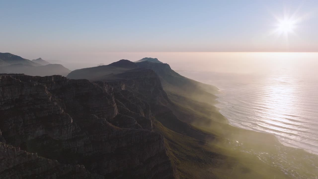 Ripresa aerea con drone dall'alto che sorvola la costa collinare dell'oceano, sulle montagne della città di Città del Capo