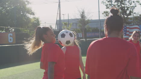 player kicking ball as female soccer team warm up during training before match