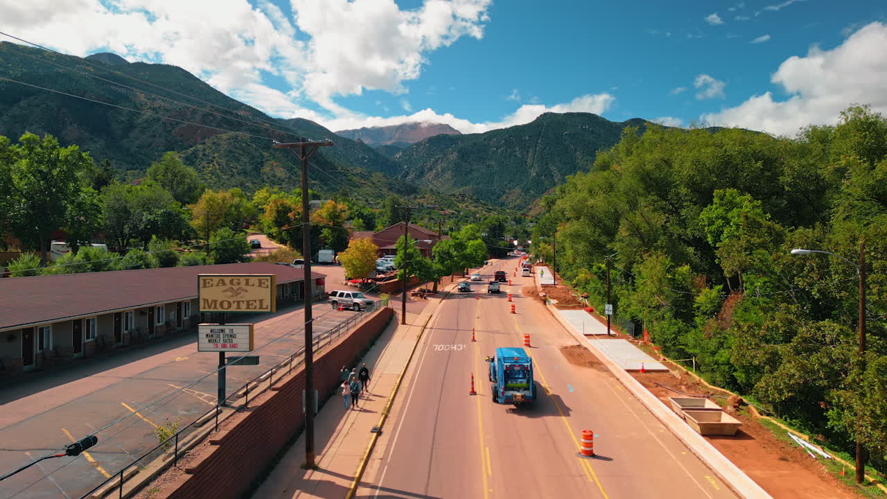 Road leading to the beautiful mountains. Drone footage over the highway with cars and people. Colorado, USA