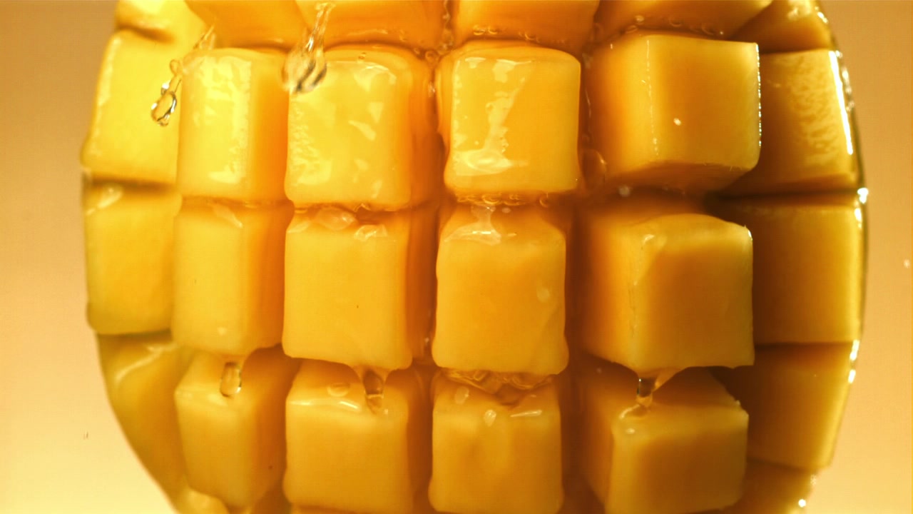Zbliżenie świeżych kostek mango z kapiącym sokiem