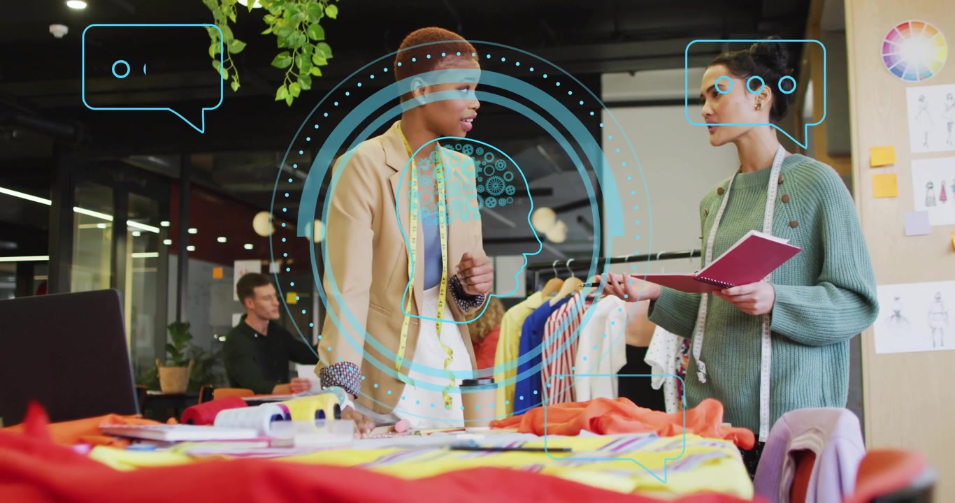 Designer leaning over examining colorful fabric swatch, partner arranging garments for fashion