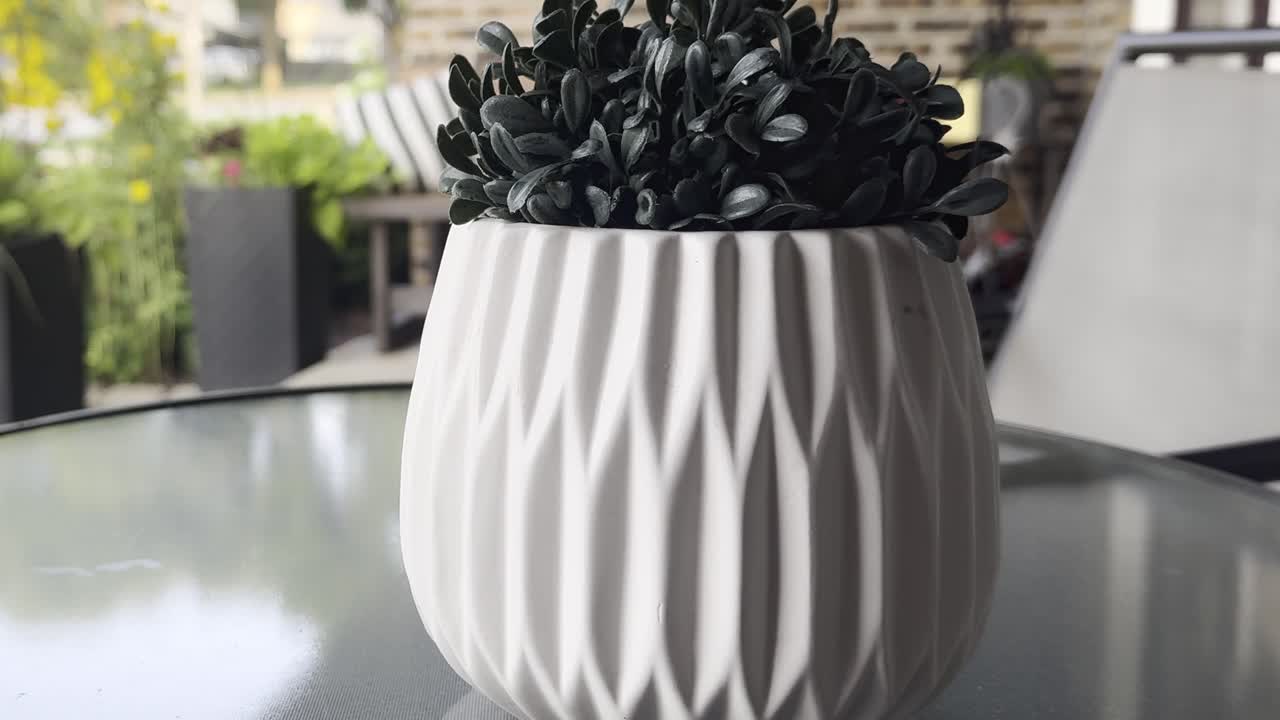 A white pot on a bistro table sits on a sunny porch on a tranquil and peaceful morning