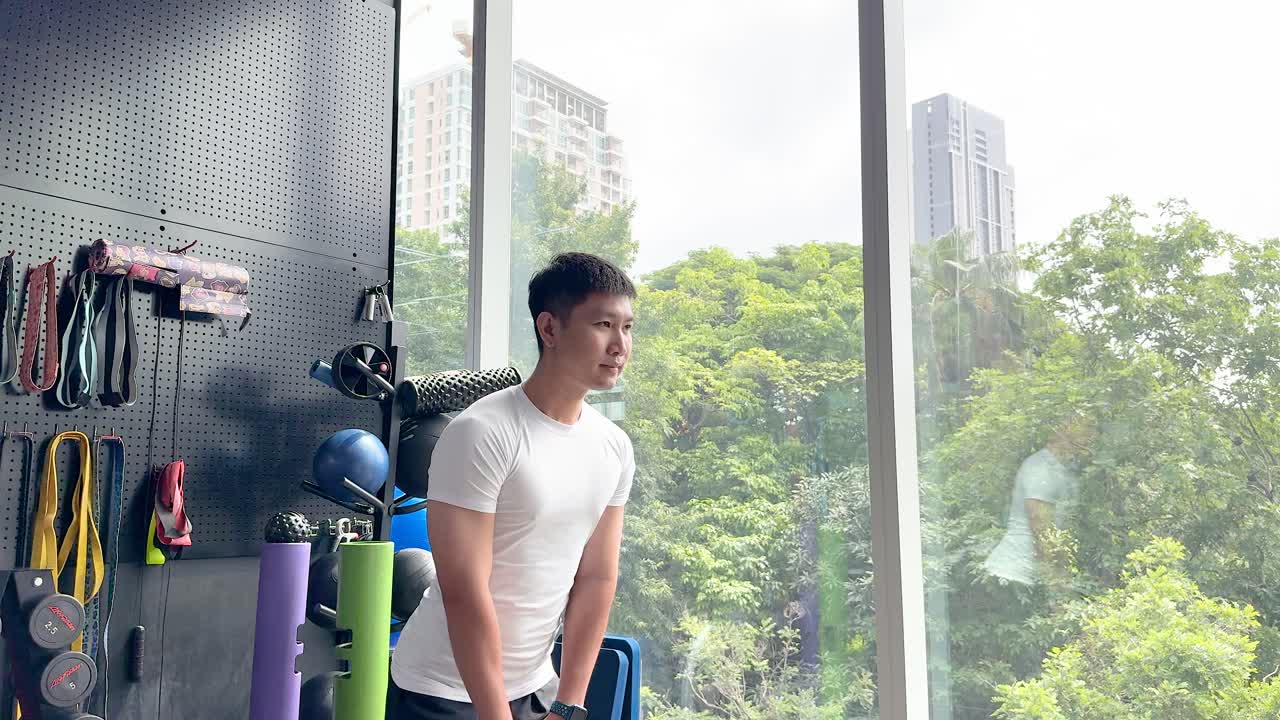 Person performing kettlebell swings in a bright urban gym with cityscape and natural light