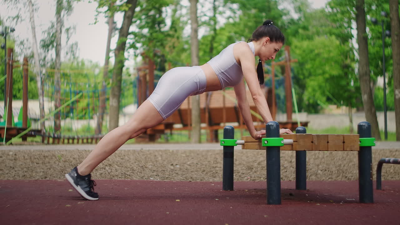 atleta femenina haciendo flexiones de banco para el entrenamiento de fuerza en el parque de la ciudad en verano. mujer deportiva entrenando al aire libre