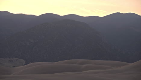 Mountains-looming-over-sand-dunes-in-early-morning,-Great-Sand-Dunes-Natl-Park