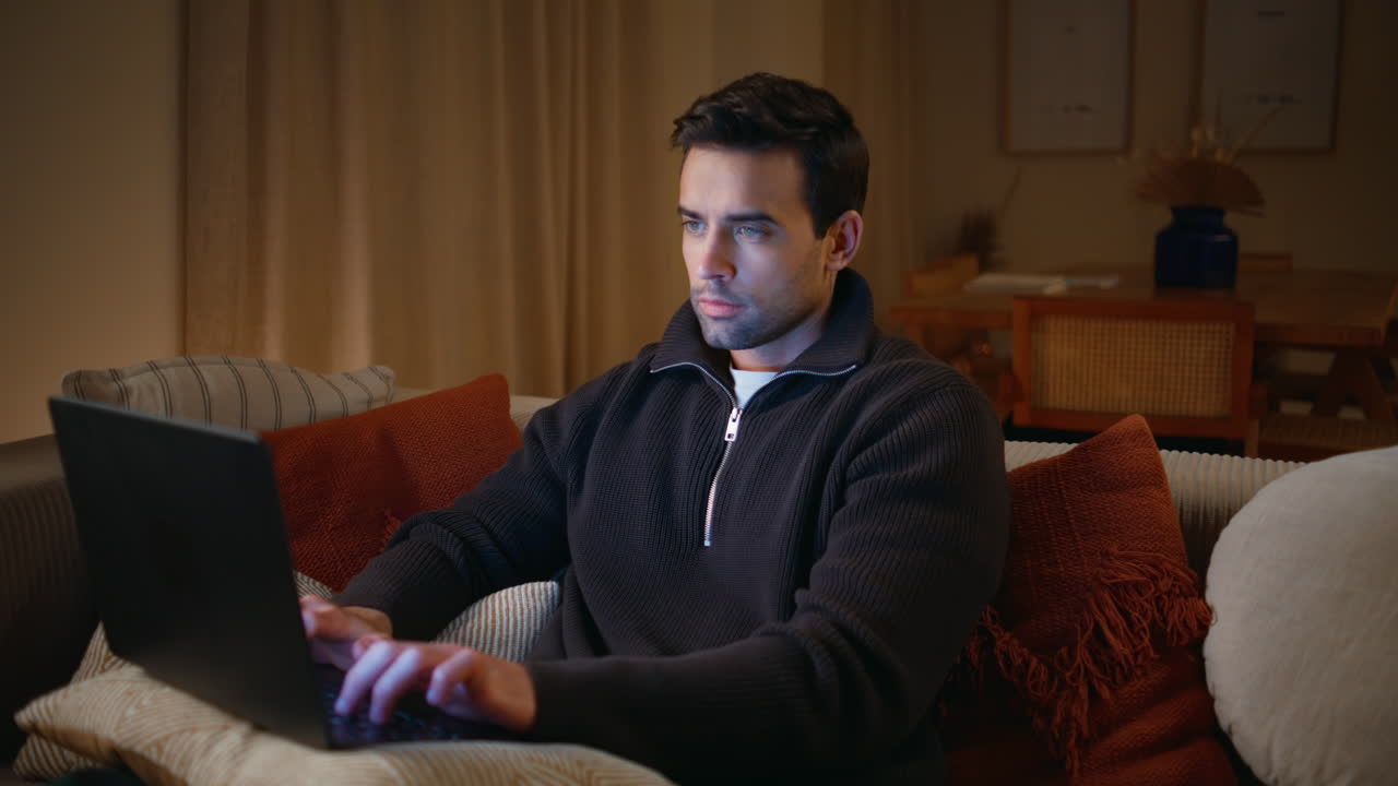 Serious freelancer working dark home on sofa closeup. Smart programmer typing