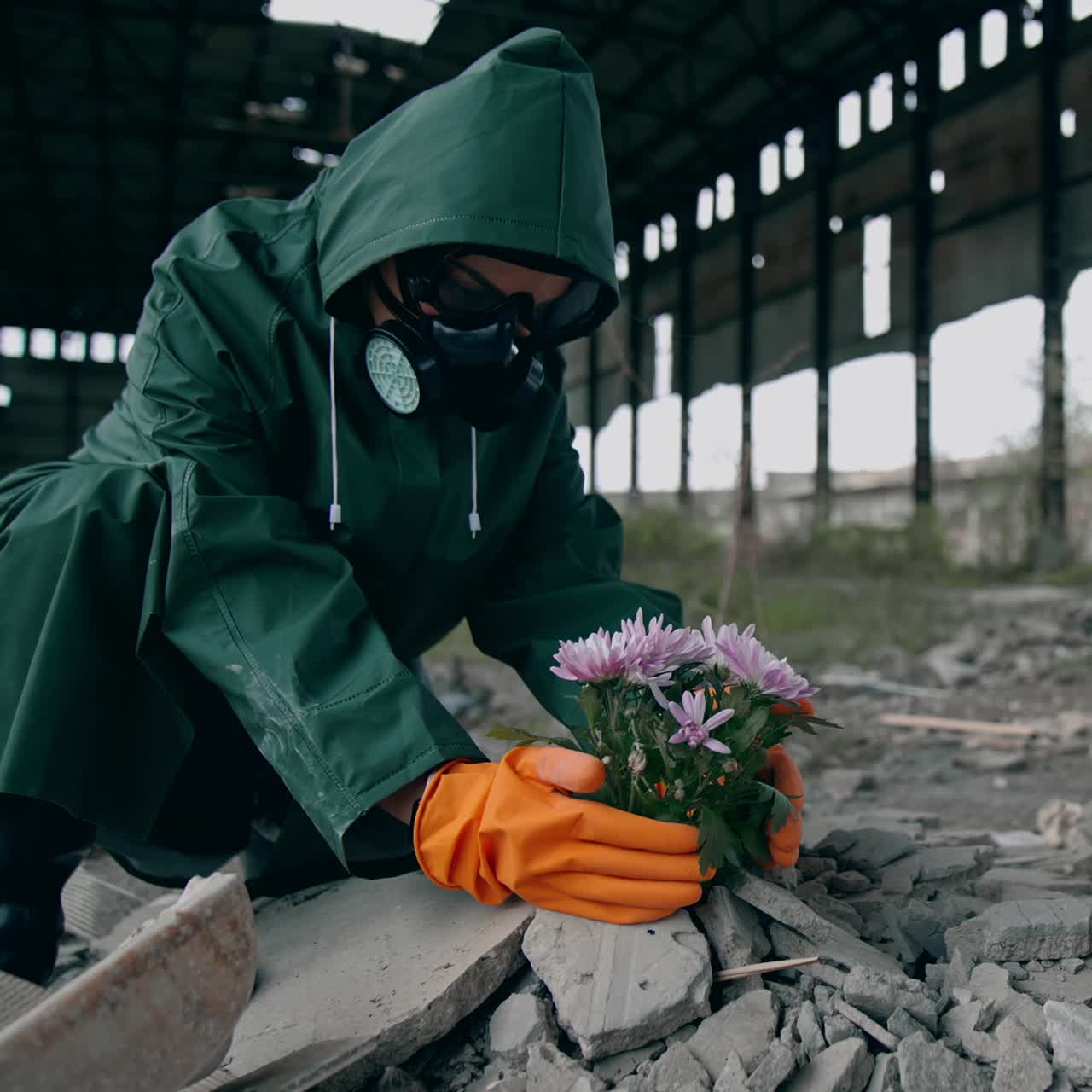 Ekolojik felaket. Koruyucu giysili ve gaz maskeli ekolojist, kimyasal saldırı olan izole bir yerde çiçekleri kurtarmaya çalışıyor.