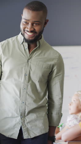 video of happy african american male teacher during lesson with class of diverse pupils