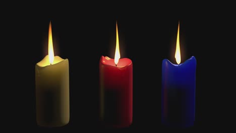 three multi-colored candles are burning on a transparent background for chromakey.