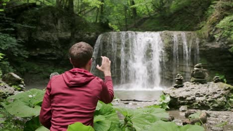 photographer working out his polarizing filter with a beautiful waterfall in the background