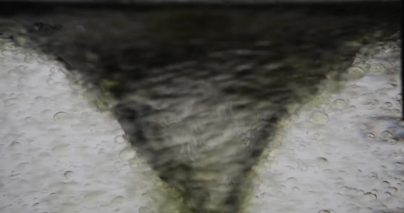 Acqua scura e torbida vortica violentemente formando un forte mulinello