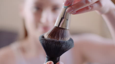 young woman using brush and powder while doing make up 1