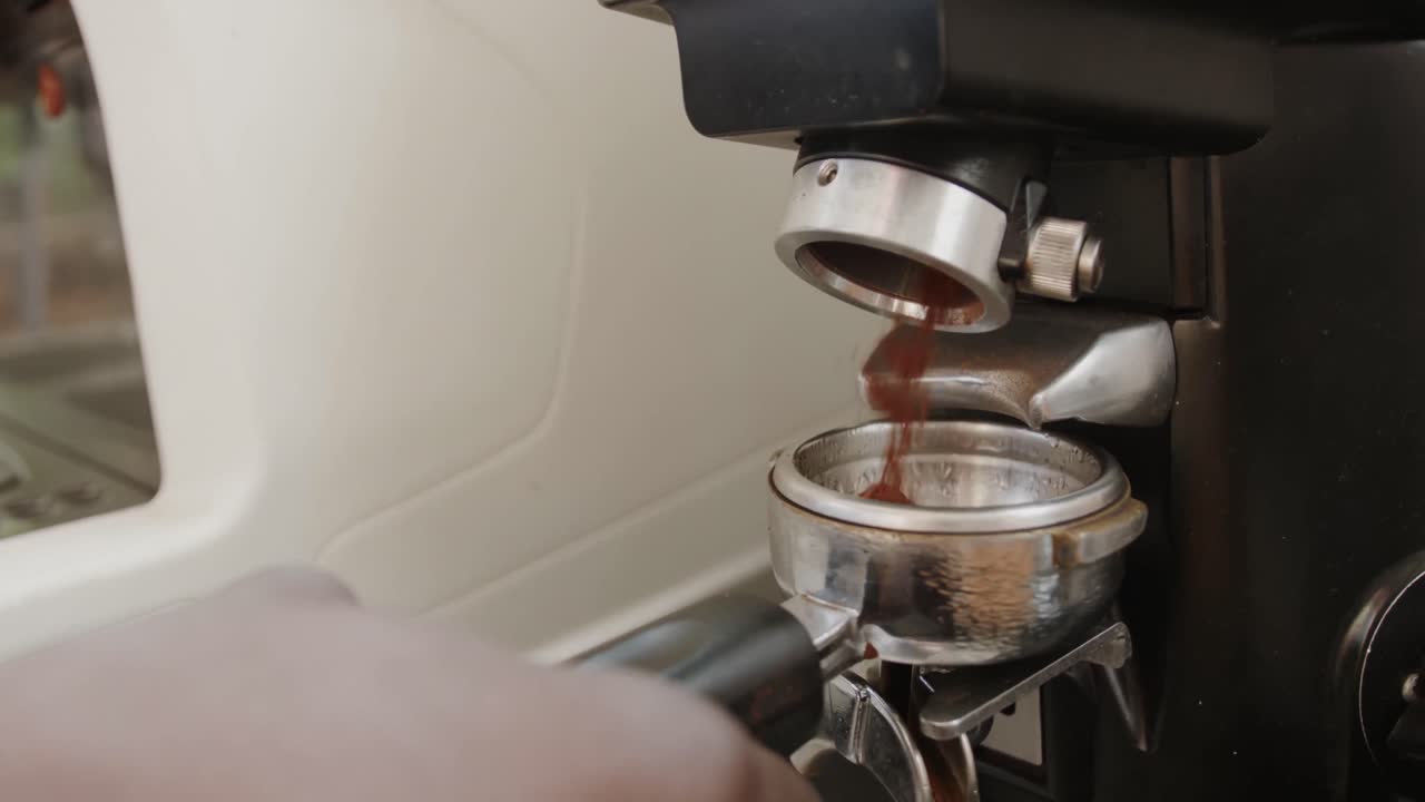 un primer plano de un barista afroamericano preparando café en una máquina en una cafetería, en cámara lenta.