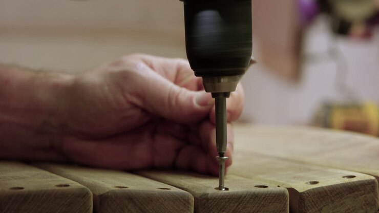 Man using drill to screw in screw on wood garage workshop project