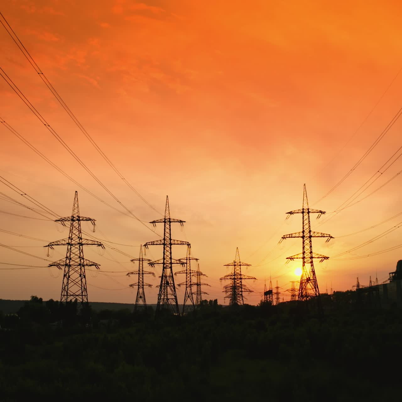 Electricity pylons at sunset. Transmission towers. Silhouette of high-voltage electic towers that transport electric power from generating stations to electrical substations. Aerial view