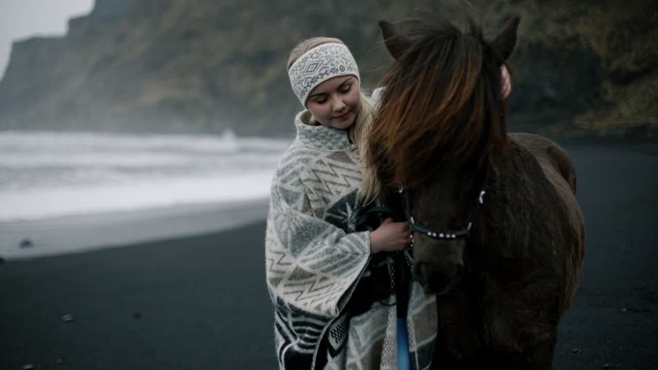 Woman hugging a horse on a black sand beach in Iceland