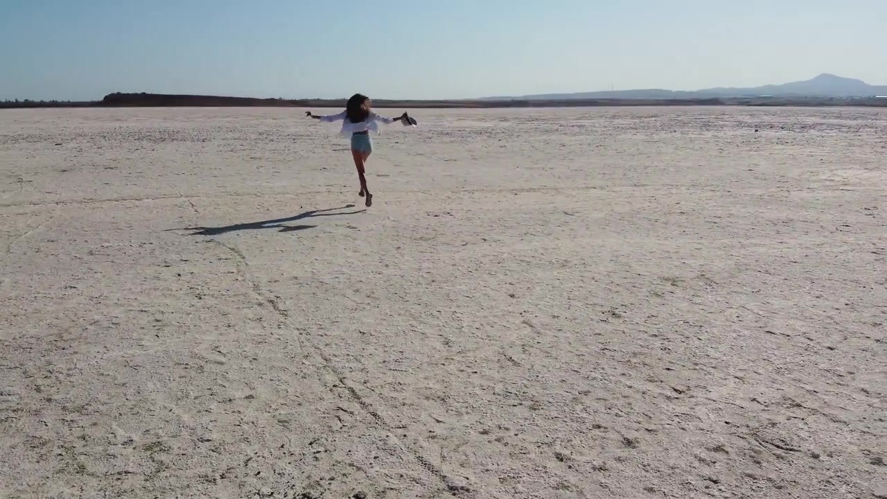Lone figure traverses cracked earth of a parched lake symbolizing drought and resilience cracked