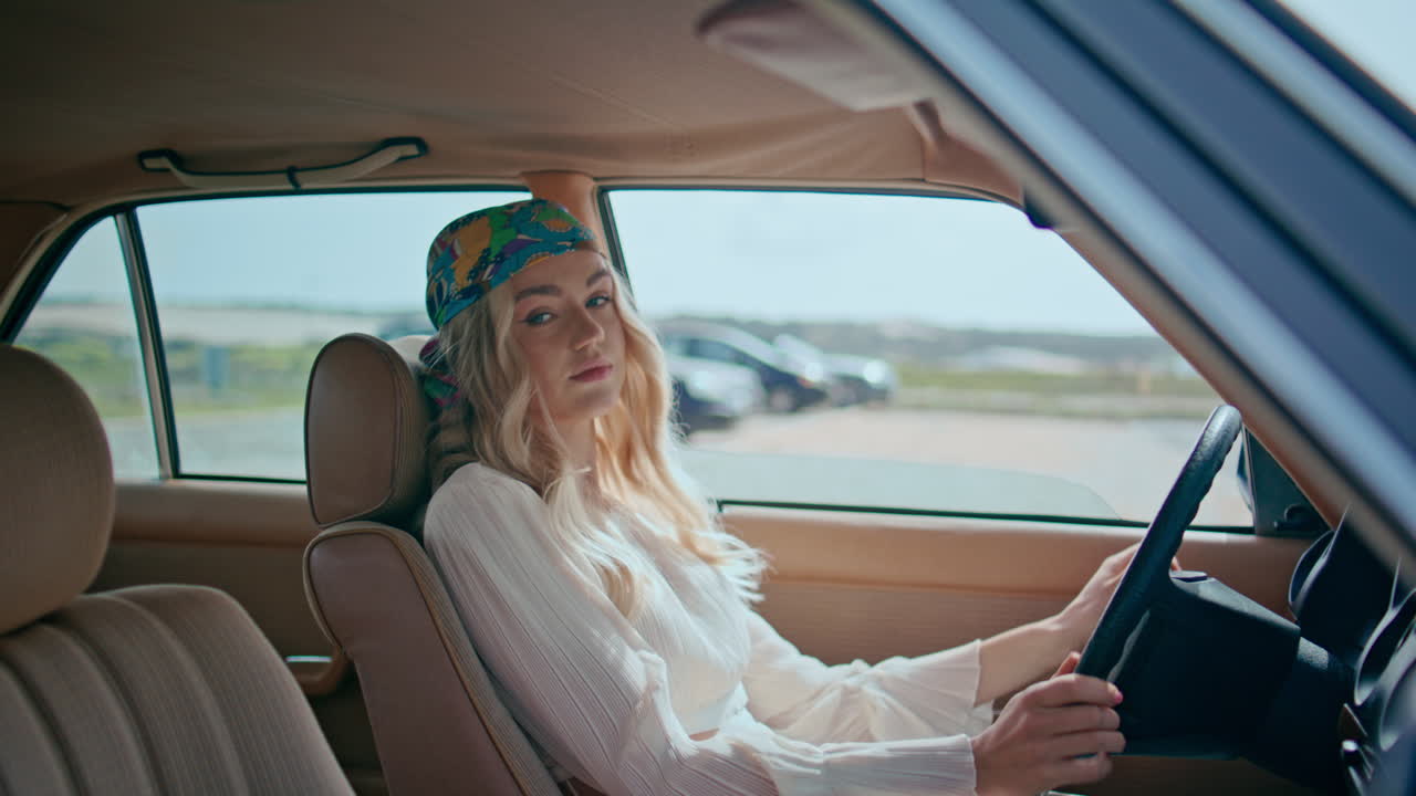 mujer sentada en un automóvil cómodo en un close-up de bandana. modelo posando en un coche retro