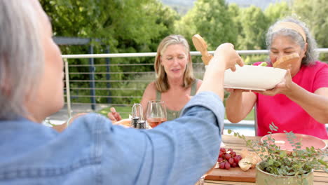 senior caucasian and biracial women enjoy a meal outdoors