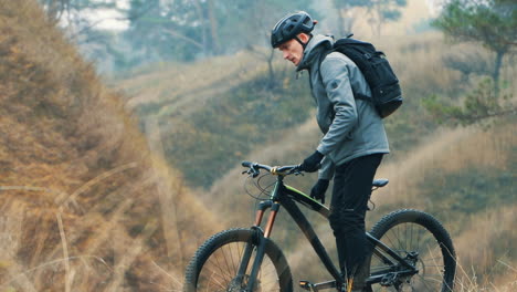 ciclista masculino que lleva una bicicleta de montaña en la colina