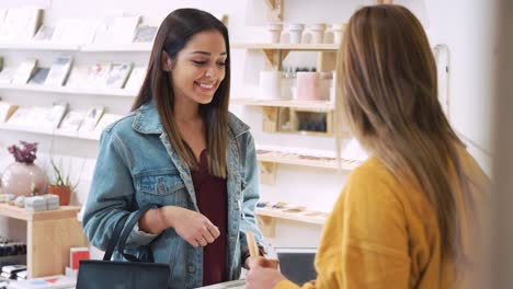 customer paying for clothes at sales desk with credit card in fashion store