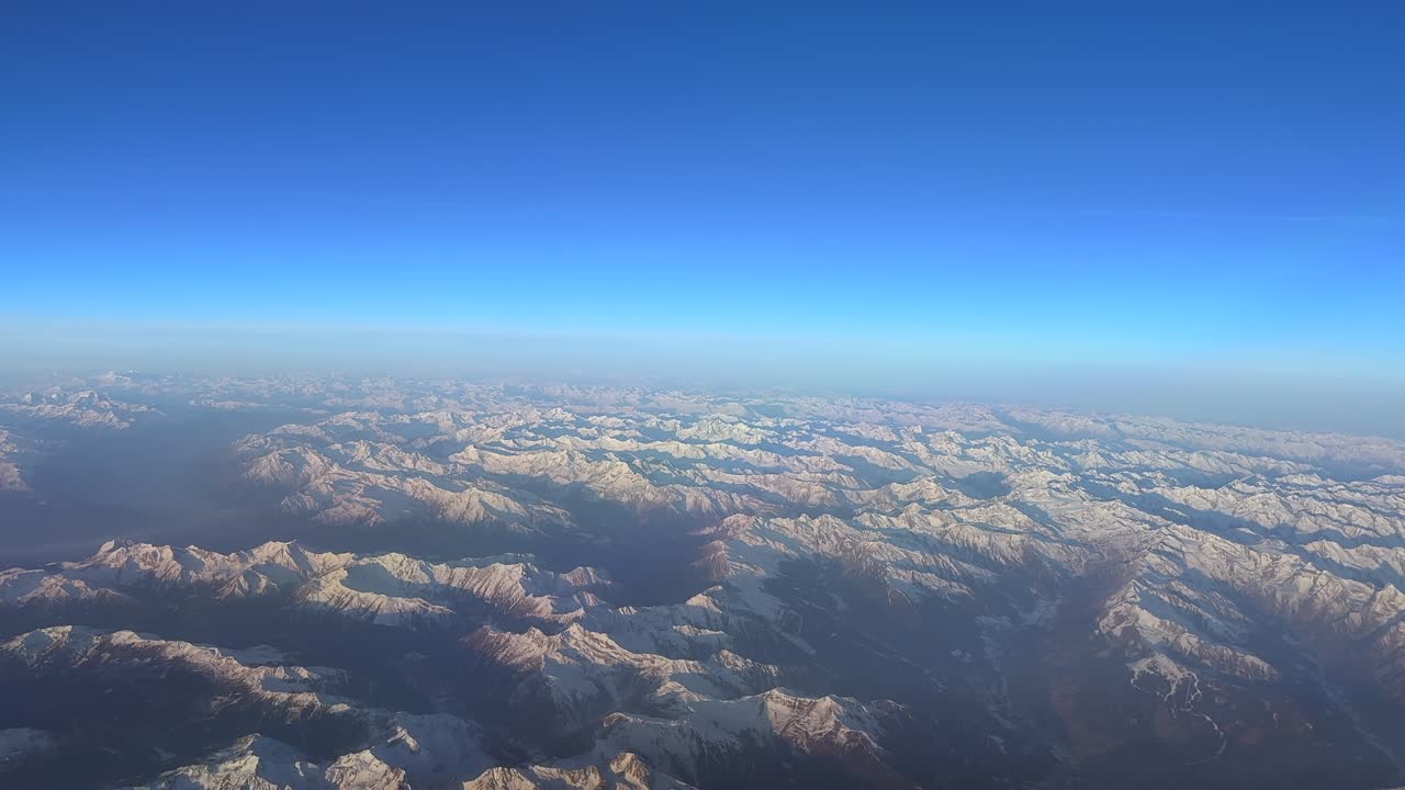 飛行機のコックピットから撮影された、雪に覆われたアルプス山脈の山頂の空撮。