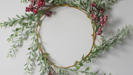 video of circular christmas leaf and berry decoration with copy space on white background