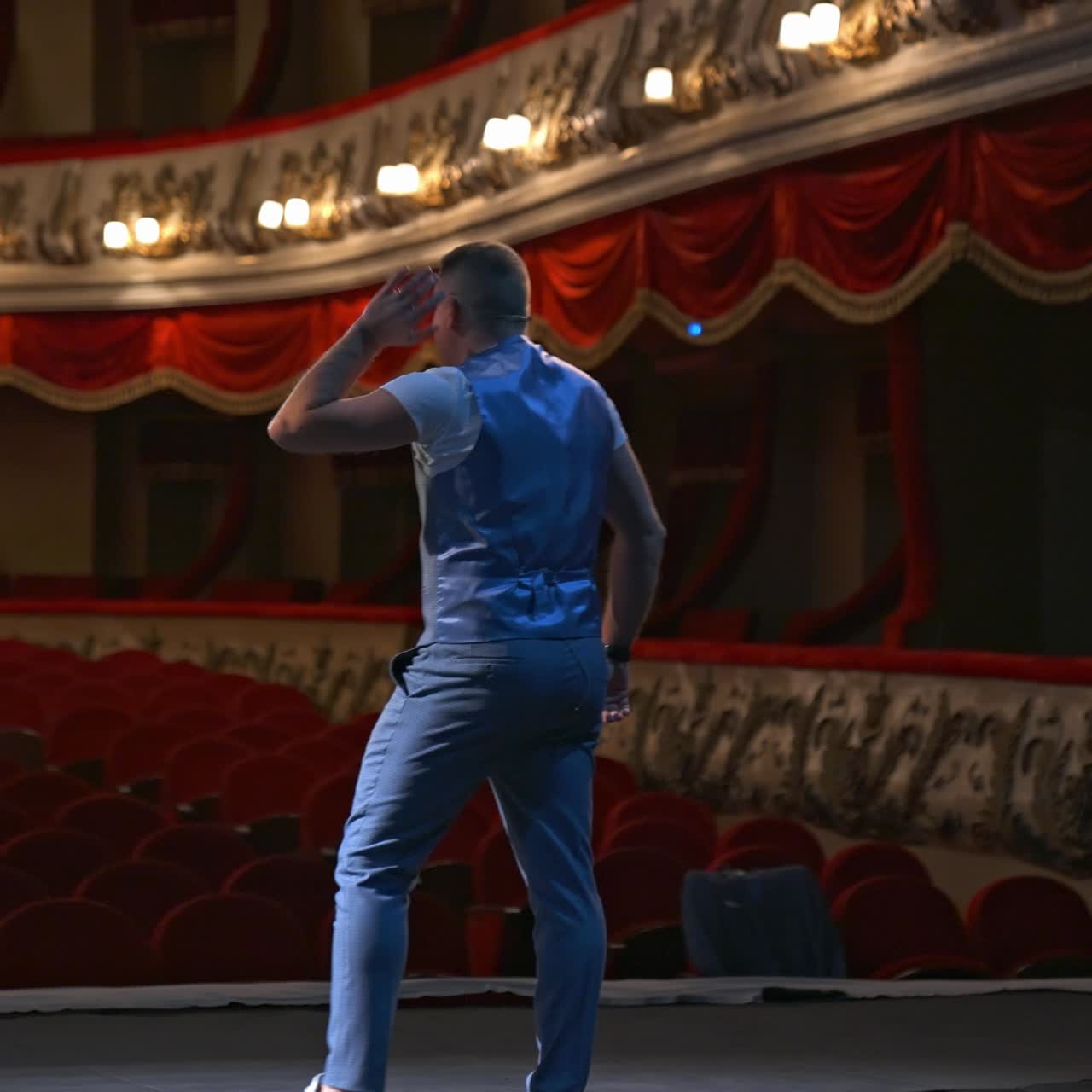 Actor on classic theatre stage. Man is speaking in spotlights during the performance. Back view video