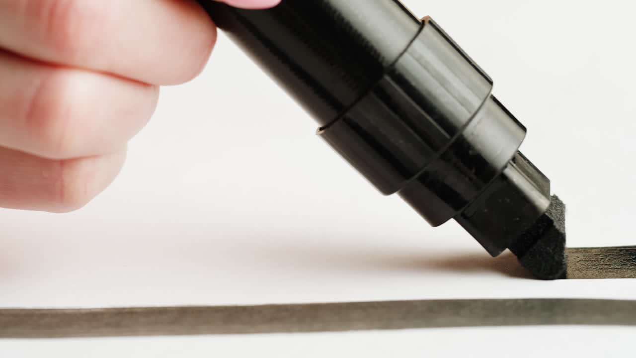 Close-up of Hand Drawing a Thick Black Line with a Marker