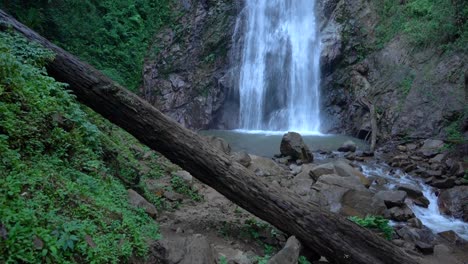 slow motion tilt revelation of a seventy meter high waterfall in the forest near chiang rai, thailand