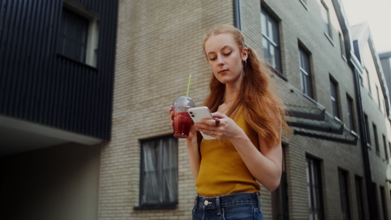 joven usando un teléfono inteligente mientras bebe un batido en la ciudad