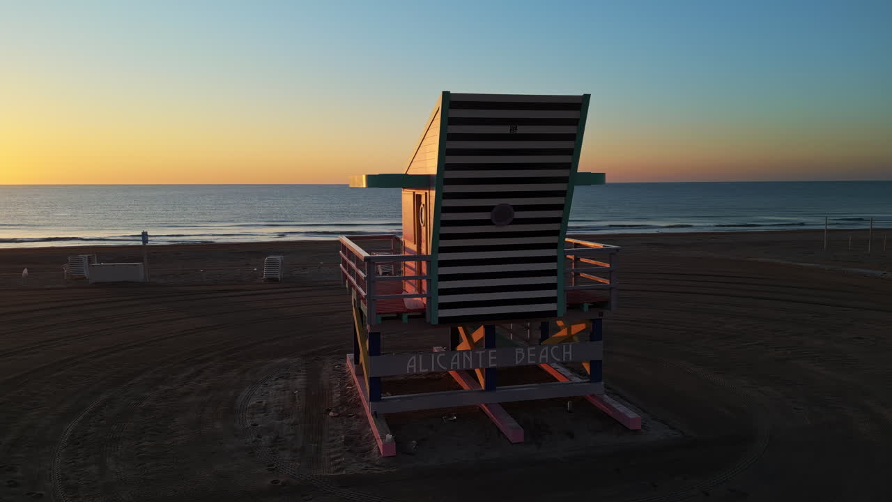 Aerial drone view of a colourful lifeguard tower on the San Juan Beach in Alicante, Spain at sunset