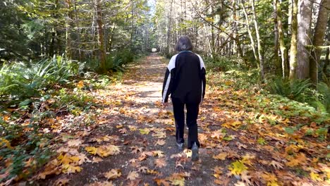 woman walking on leaf covered path in forest in autumn in canada