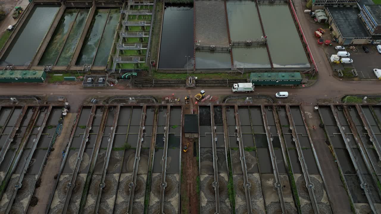 Overhead drone aerial footage of huge sewage treatment plant with circular tanks, settling pools, silos and complex industrial layout Leicester