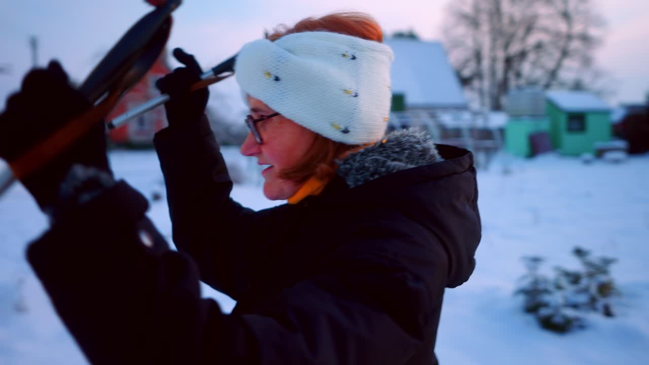 Anziana signora che si diverte sciando su una strada innevata in un villaggio in Lituania.
