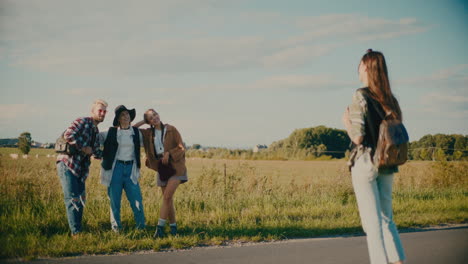 woman photographing friends posing in meadow