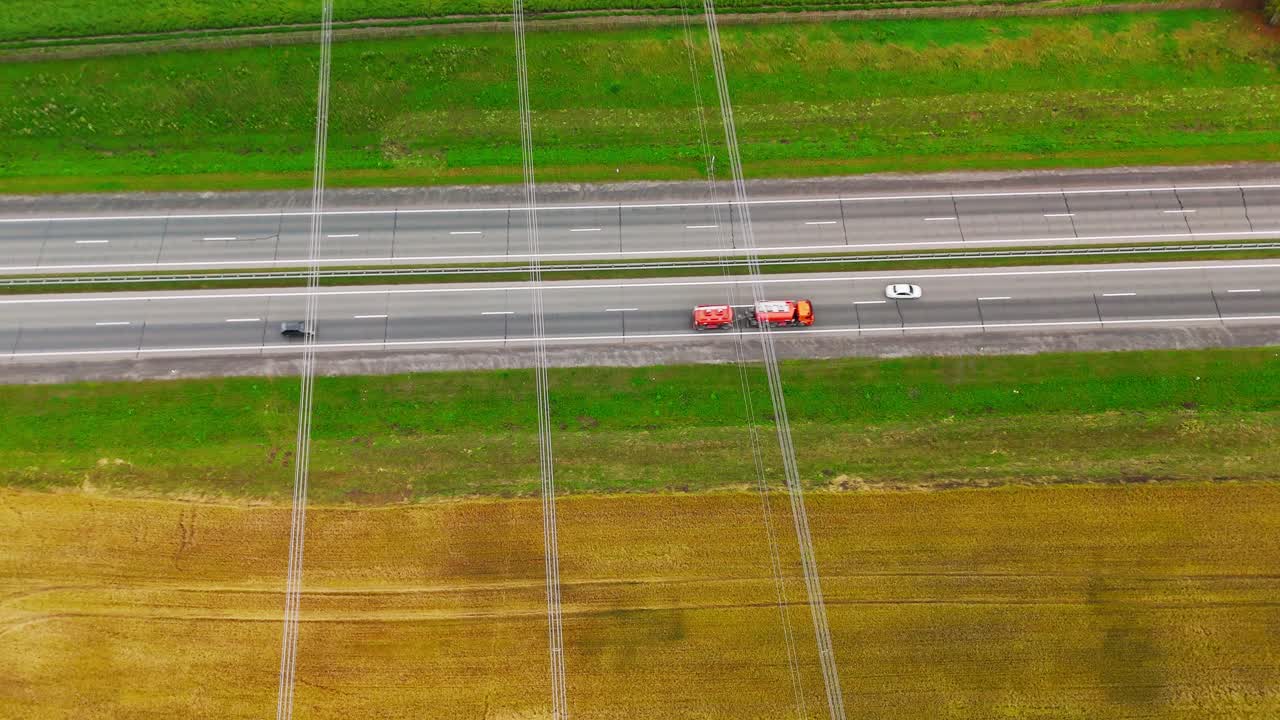 車と畑と送電線が見える高速道路の空撮。