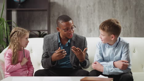 African-American man tutor explains topic to smart children