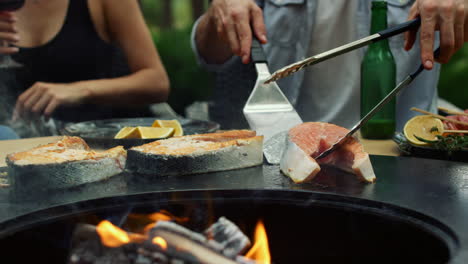 unrecognizable man controlling fish preparation outside. guy using kitchen tools