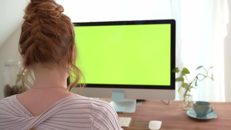 Handsome Woman Sitting at her Desk using personal Computer with Green Screen
