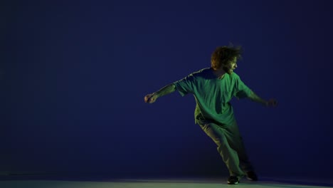 stylish young man, hip-hop dancer dancing isolated over dark blue background in neon light. modern dance art, fashion, youth, ad, style. 4k, video
