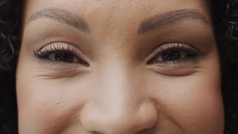 portret van een gelukkige afrikaans-amerikaanse vrouw die glimlacht en naar de camera kijkt in de tuin, slow motion