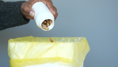 a person throws away pills in the trash.