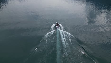 primer plano de un barco turístico y un hombre haciendo esquí acuático en un lago suizo