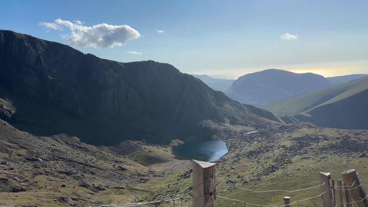 Scenic view of Mount Snowdon summit with mountain peaks, deep valley, rocky slopes, and clear lake in Snowdonia National Park. A breathtaking landscape showcasing nature's beauty and serenity.