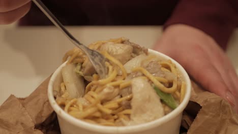 thai green curry noodles with meat mixed being forked for meal, closeup