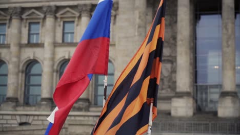 Russian-flag-and-flag-of-ribbon-of-Saint-George-waving-in-wind,-slow-motion