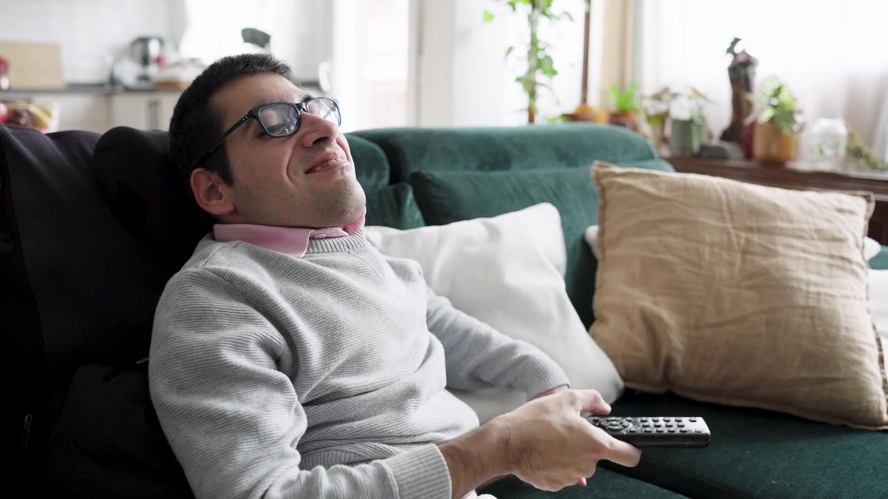 Giovane uomo che si rilassa sul divano e usa il telecomando
