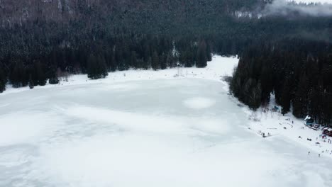 People-on-banks-of-frozen-Saint-Ann-volcanic-crater-lake,-Romania