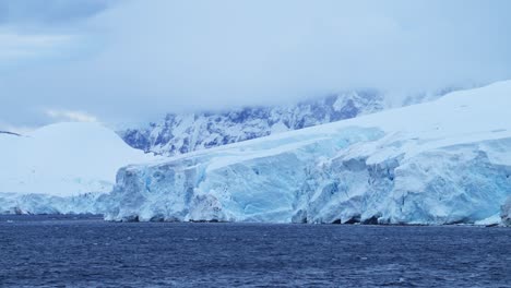 glacier and ocean in antarctica on the coast, ice and coastal winter scenery, icy glacial landscape with a large glacier next to the sea on the antarctic peninsula with a crevass and ice formations